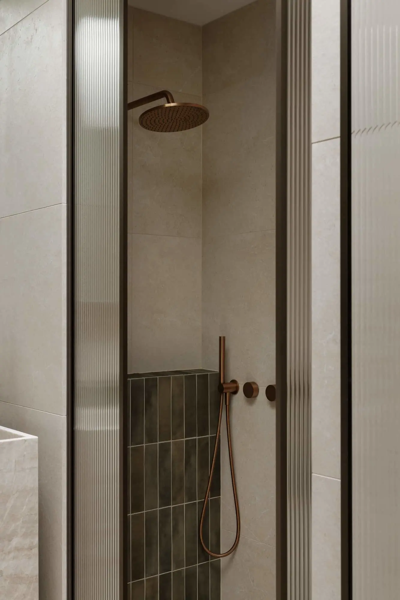 Modern shower stall with beige tile walls, dark green accent tiles, and copper rainfall showerhead and handheld fixture.