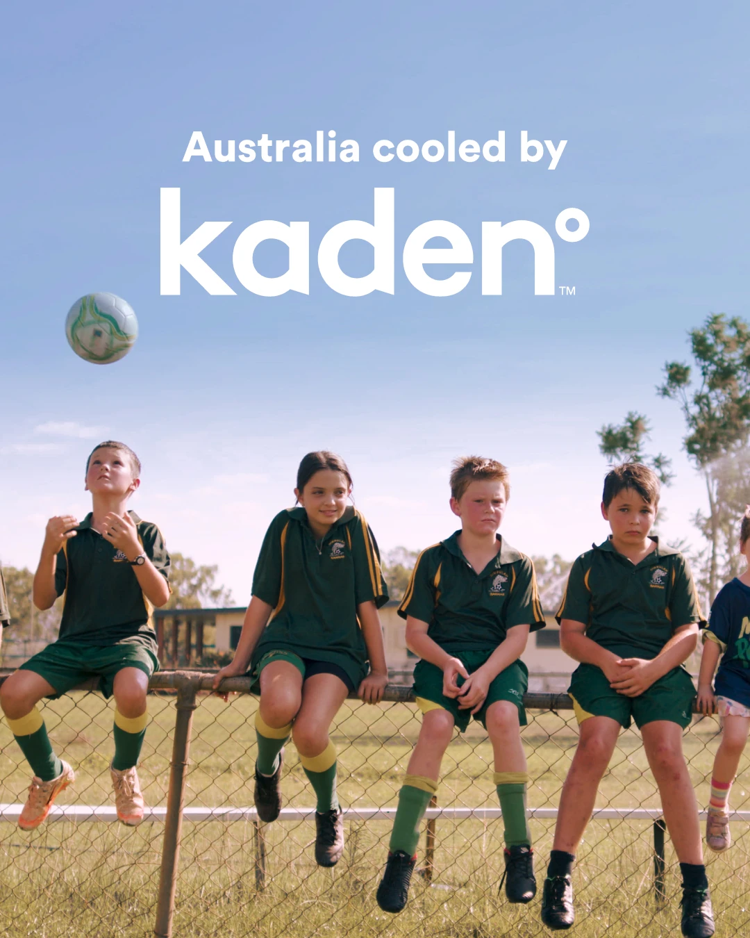 Children in green sports uniforms sitting on a fence with text "Australia cooled by kaden°" against blue sky.