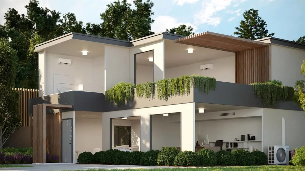 Modern two-story white house with wooden accents, balcony with hanging plants, and landscaped garden surrounded by trees.