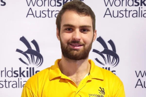 Person in yellow polo shirt standing in front of WorldSkills Australia backdrop