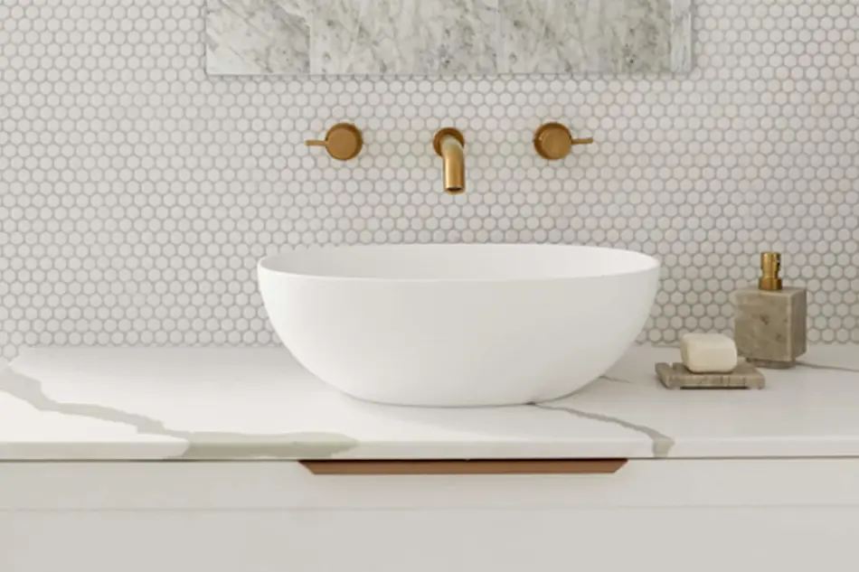 Modern bathroom with white vessel sink, gold wall-mounted faucet, hexagonal tile backsplash, and marble countertop.