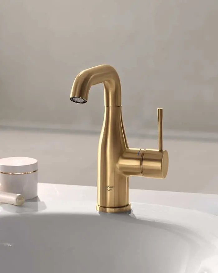 Modern brushed gold bathroom faucet with curved spout and lever handle mounted on white sink basin.