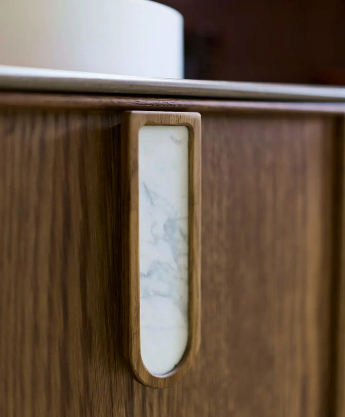 Close-up of modern bathroom fixtures showing wooden cabinet with marble inlay and white sink.