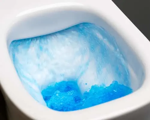 White toilet bowl with blue cleaning solution swirling in the water