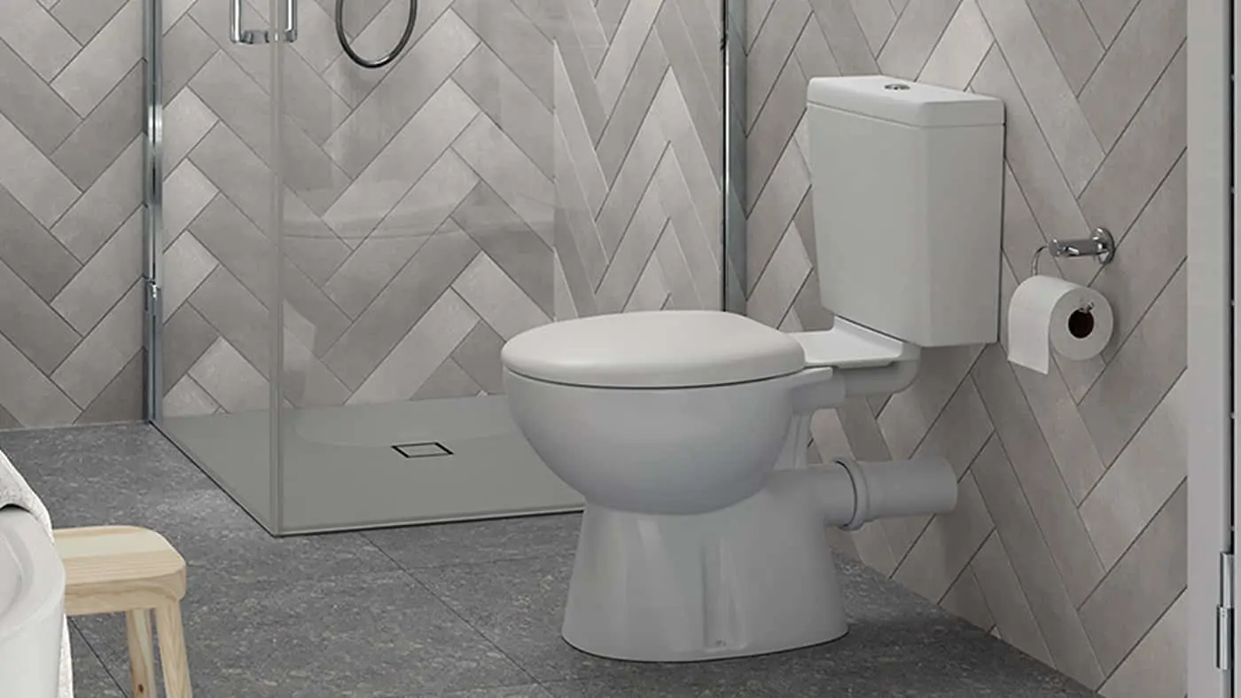 Modern bathroom with white toilet, glass shower enclosure, and herringbone tile walls on gray floor.