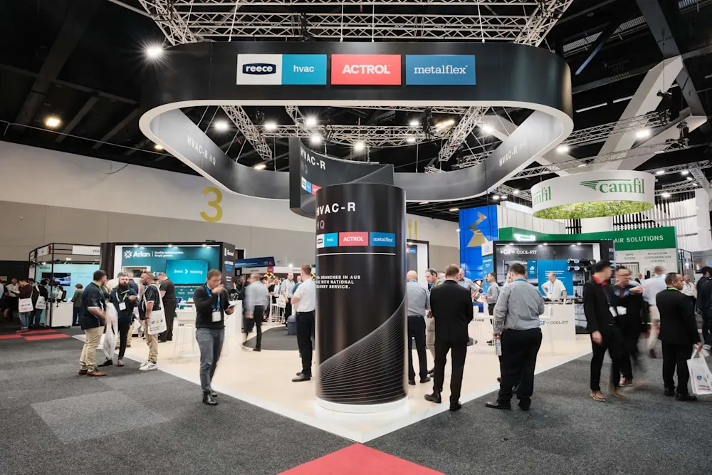 HVAC-R trade show booth with circular overhead display featuring Reece, HVAC, ACTROL, and metalflex logos, surrounded by attendees.