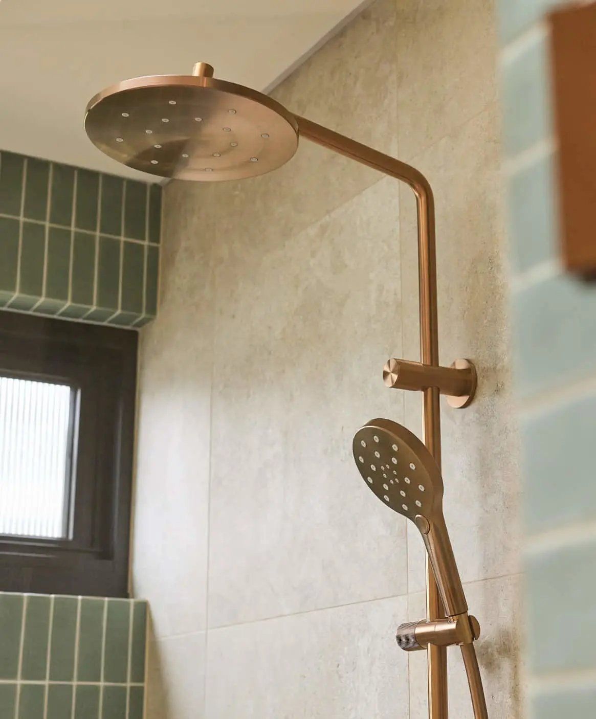 Modern bathroom with bronze fixtures: rainfall showerhead with handheld sprayer on right.