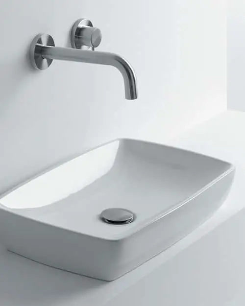 Modern white rectangular vessel sink with wall-mounted stainless steel faucet in a minimalist bathroom design.
