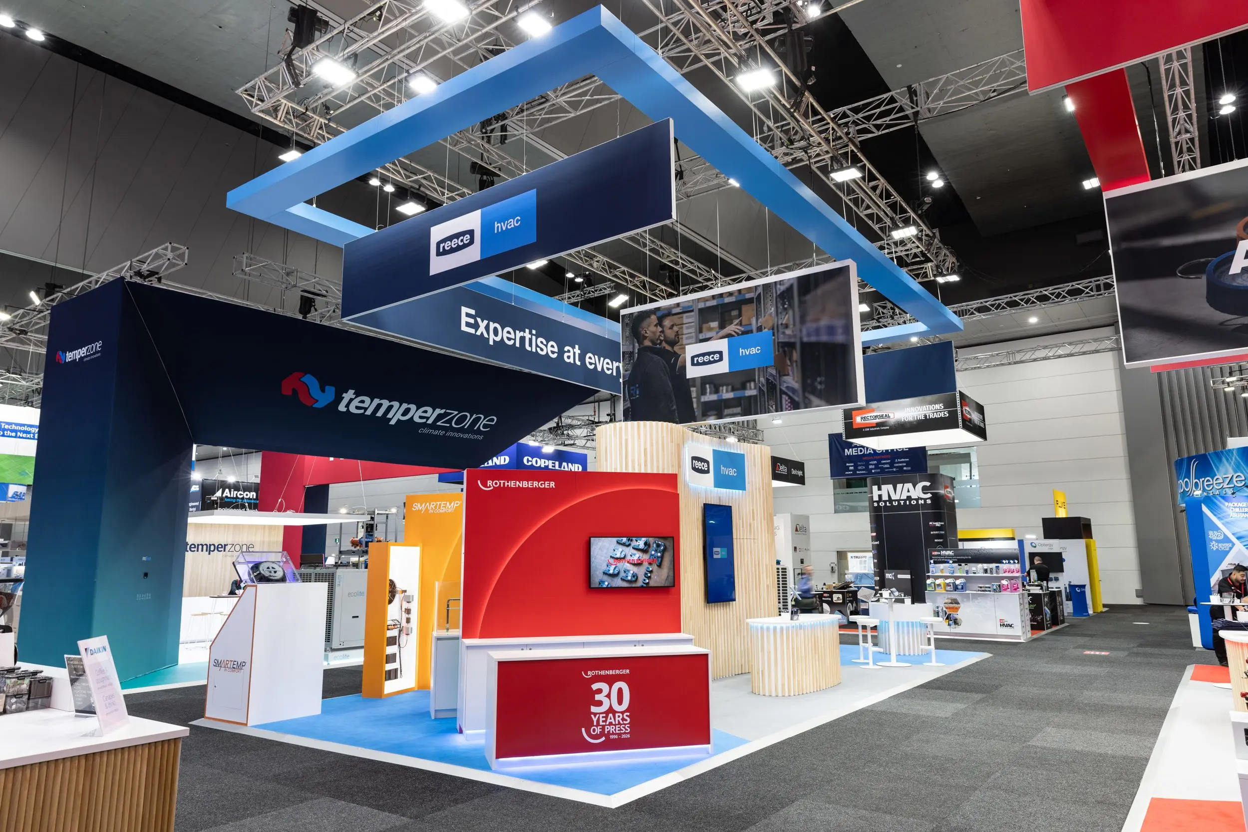 Trade show floor with Reece HVAC and Temperzone exhibition booths featuring blue, red, and orange displays.