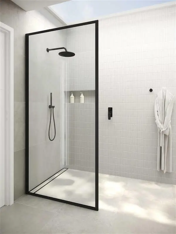 Modern shower with black frame glass door, white tiled walls, rainfall showerhead, and white bathrobe hanging nearby.
