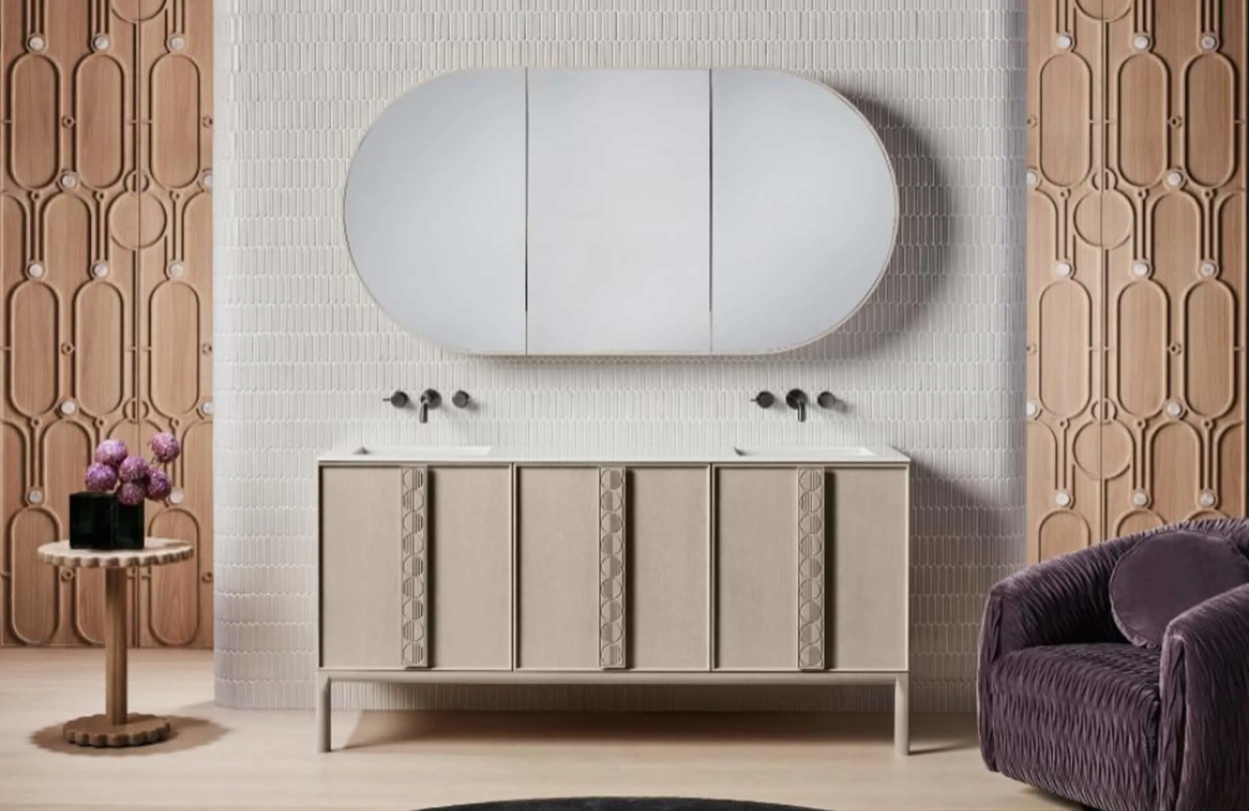 Modern bathroom with oval mirror, cream vanity, white tiled wall, wooden panels, purple flowers and velvet chair.