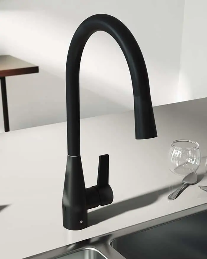 Modern matte black kitchen faucet with high curved neck on white countertop next to a glass and spoon.