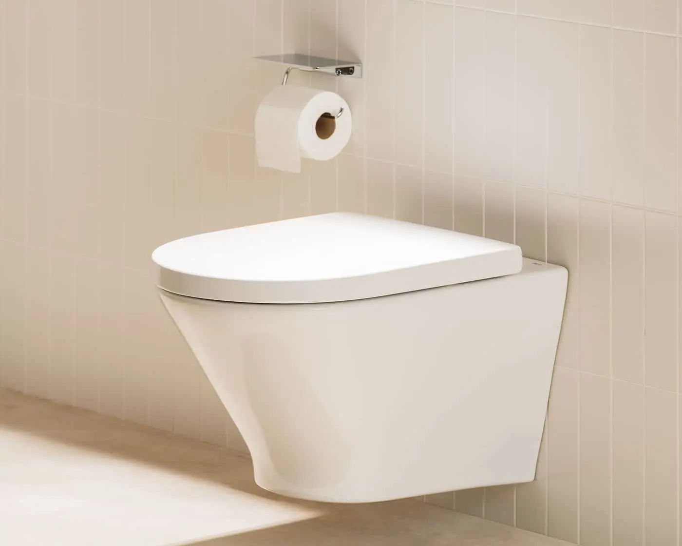 White wall-mounted toilet with closed lid and toilet paper holder above, against beige tiled bathroom wall.