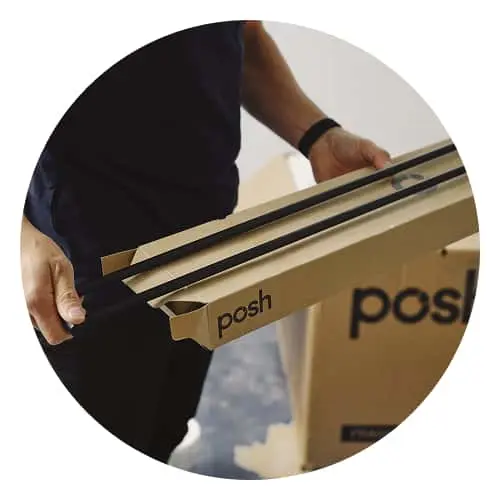Person in dark clothing carrying cardboard boxes labeled "posh" for delivery or moving.