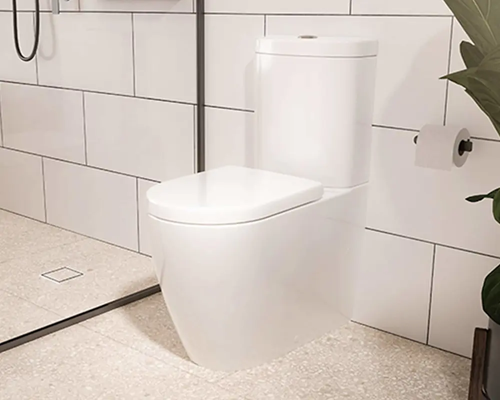 Modern white toilet in a minimalist bathroom with white tile walls, toilet paper holder, and partial view of a plant.