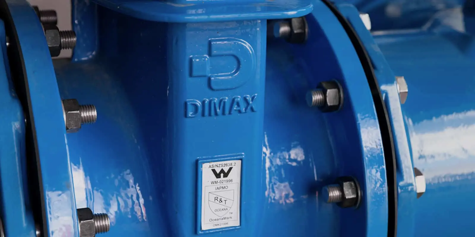 Close-up of blue DIMAX industrial pipe fitting with bolted flanges and certification label.