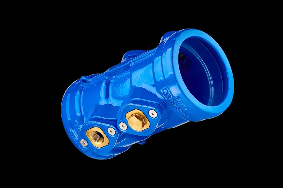 Blue plumbing pipe fitting with brass connection ports against black background.