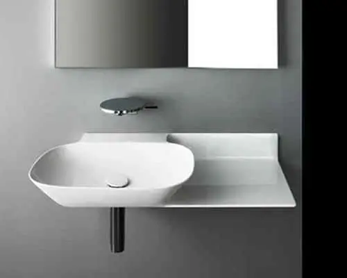 Modern white bathroom sink with curved basin mounted on wall, chrome faucet, and mirror above