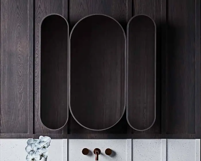 Dark wooden wall paneling with curved three-panelled mirror.