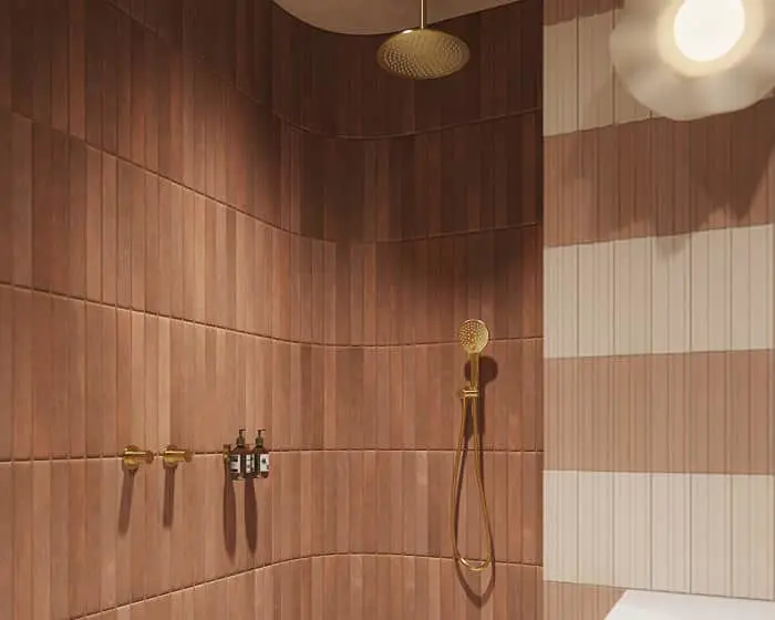 Modern shower with curved terracotta and cream tiled walls, gold fixtures, and a matching rainfall showerhead.