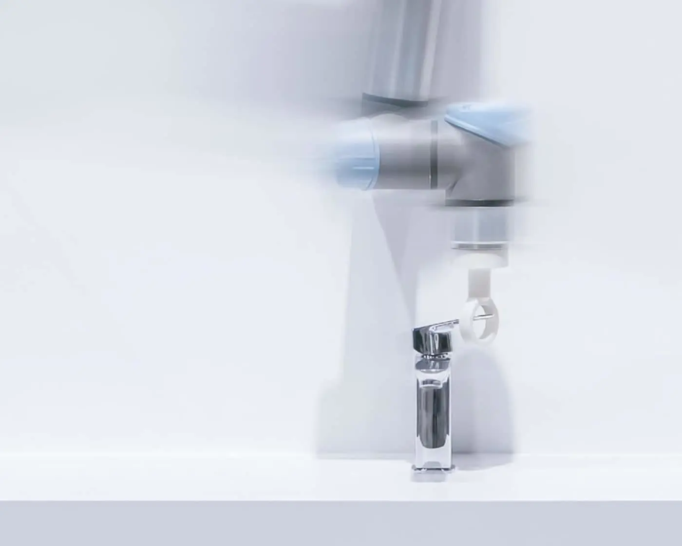 Modern bathroom sink with chrome faucet and white fixtures against a light background, creating a minimalist look.