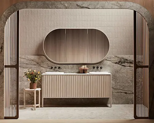 Modern bathroom with marble walls, oval mirror, ribbed vanity cabinet, and small side table with flowers.