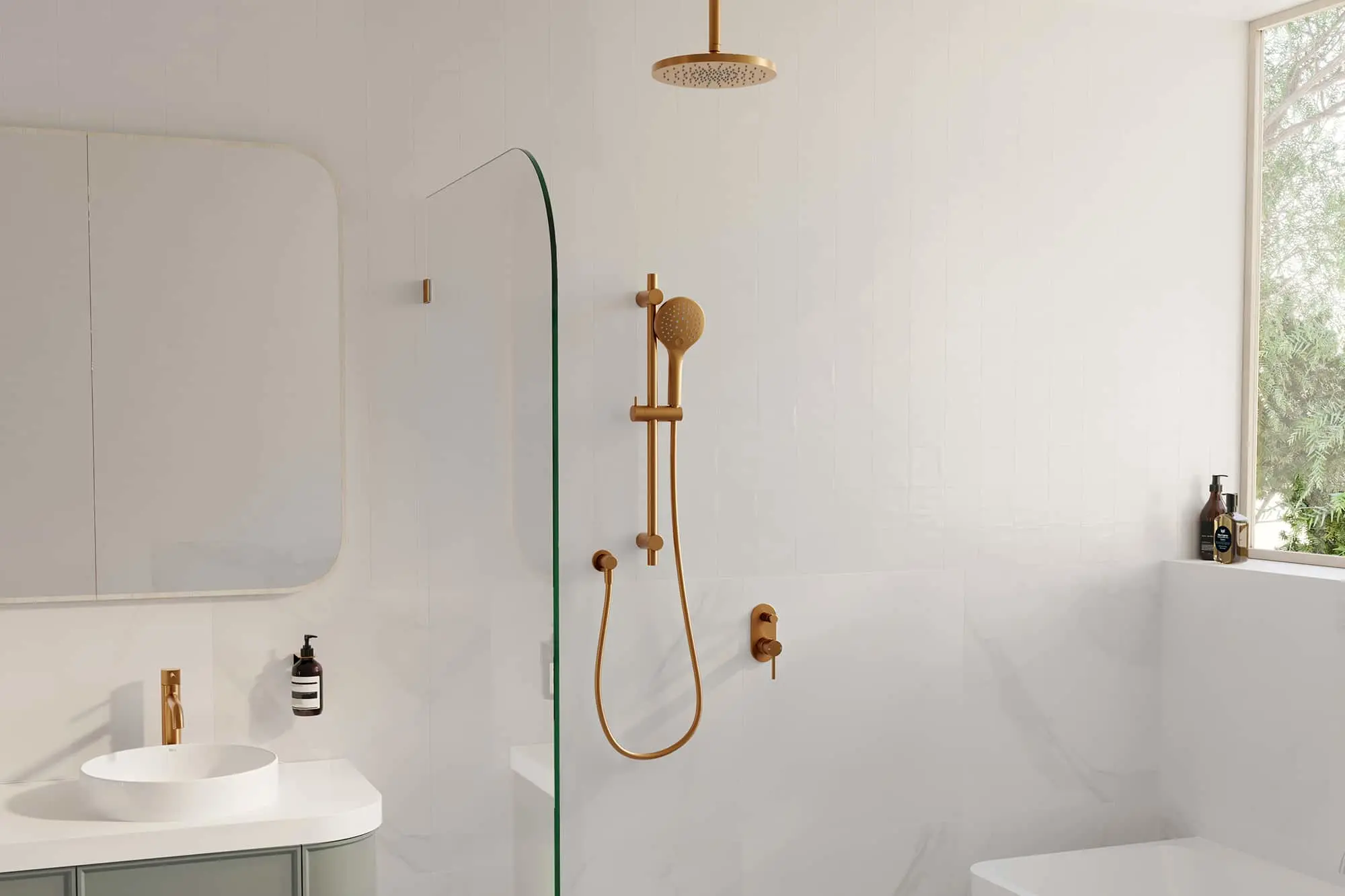 Modern white bathroom with brass fixtures featuring a rainfall showerhead, handheld sprayer, and sink beside a glass partition.