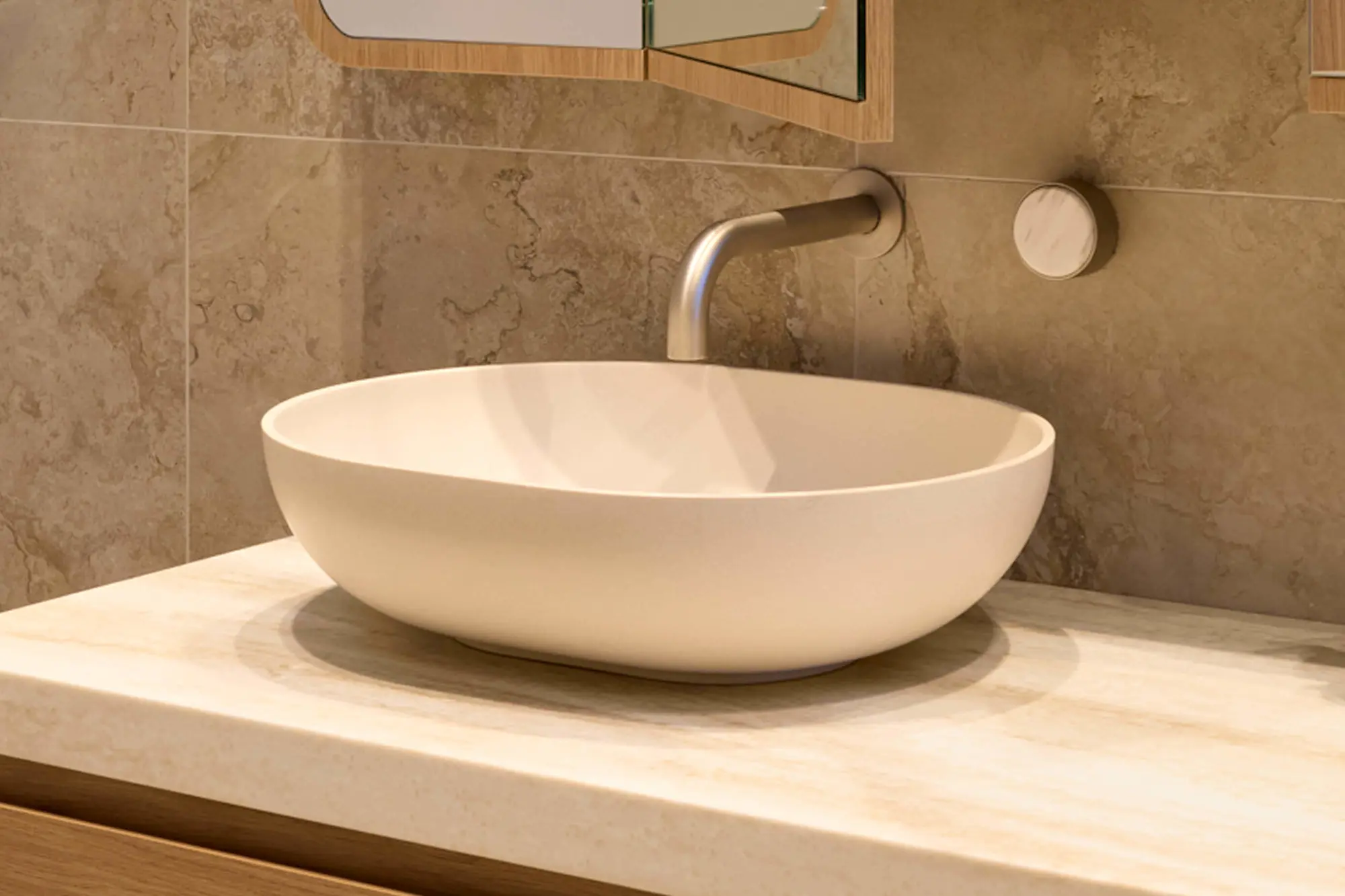 White round vessel sink on marble countertop with wall-mounted brushed nickel faucet and beige tiled wall.