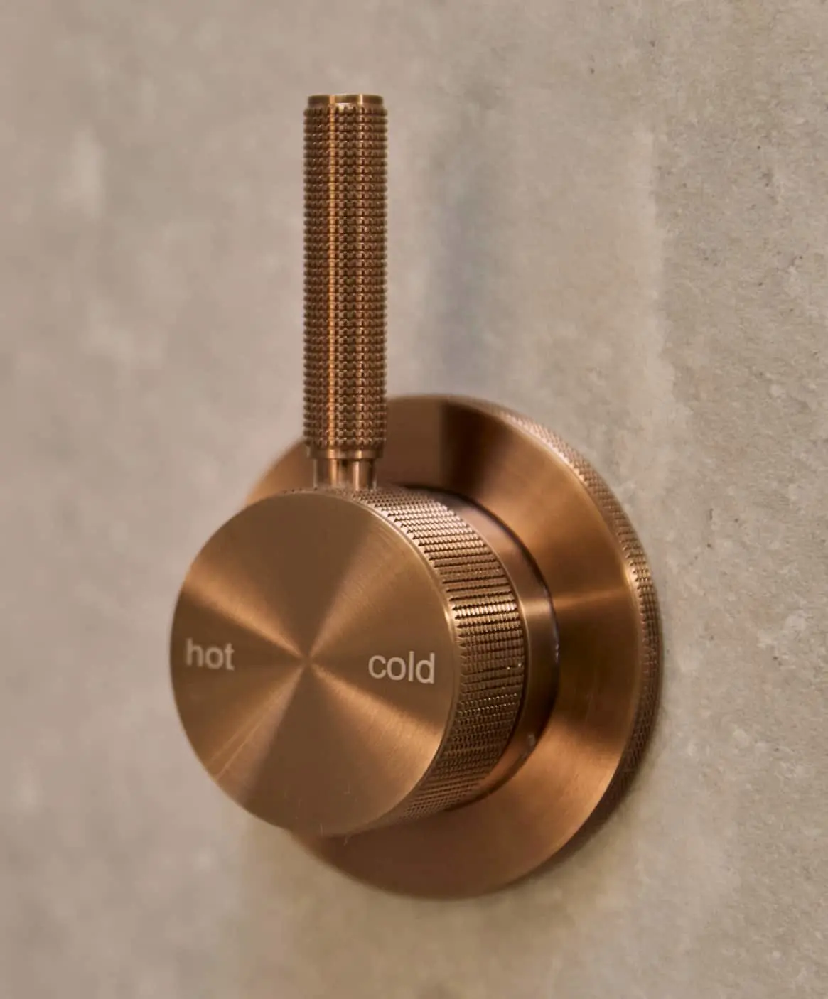 Bronze bathroom fixtures: a shower temperature control knob with hot/cold markings.