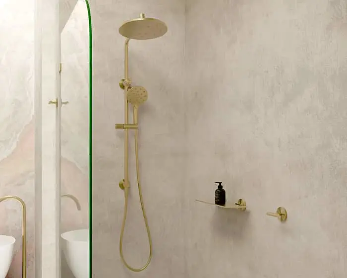 Modern bathroom with gold rainfall shower fixture, textured beige walls, and minimalist shelf holding a black dispenser.