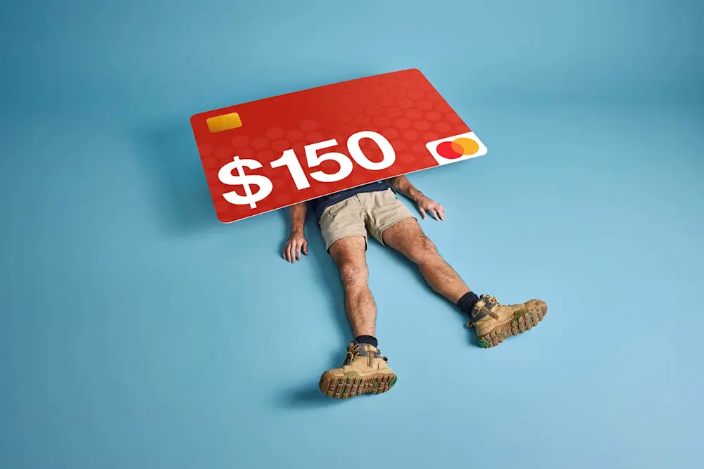 Person lying on blue background with legs visible, crushed under a large red credit card displaying "$150"
