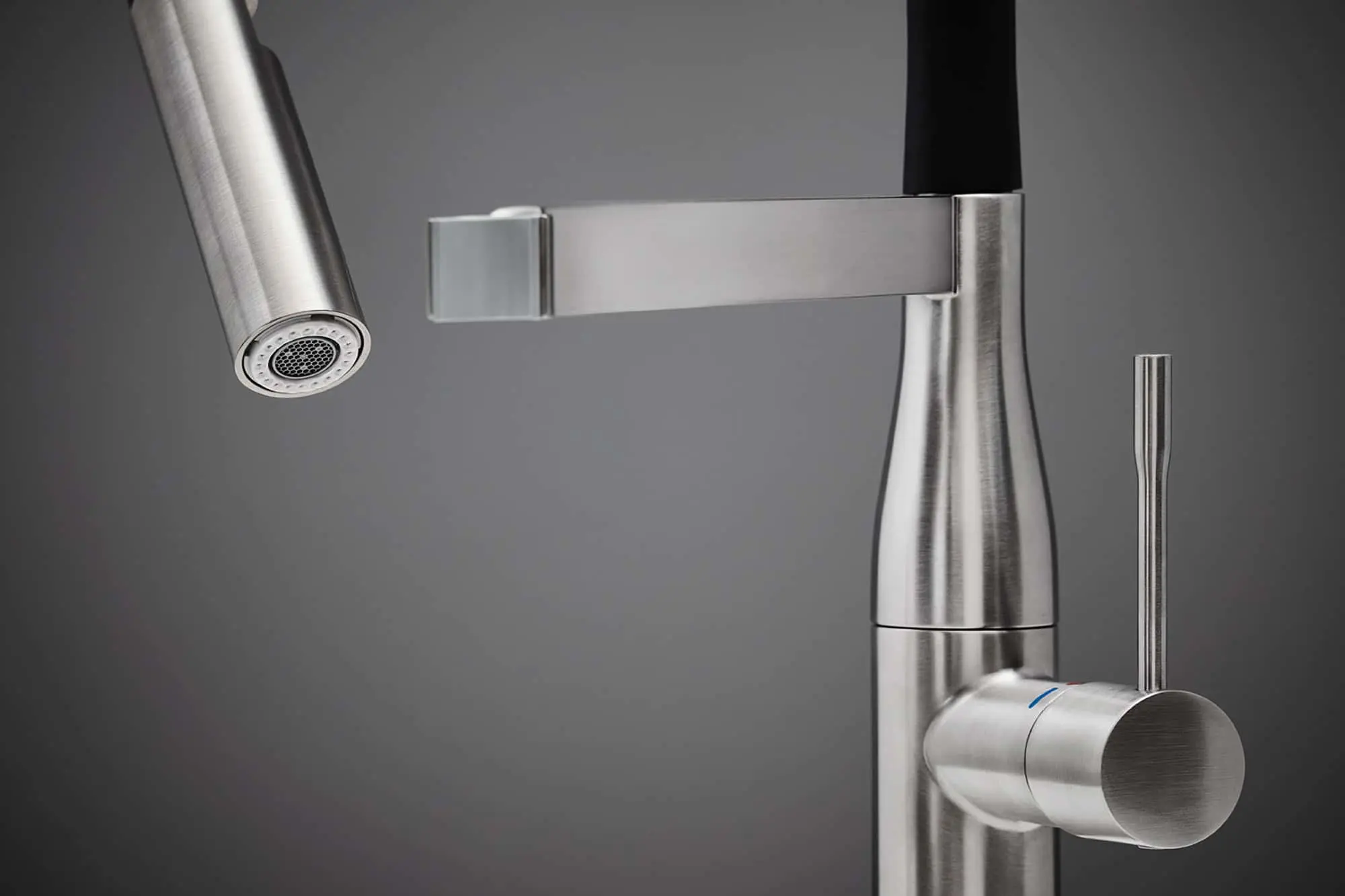 Modern stainless steel kitchen faucet with pull-down sprayer and cylindrical handle against gray background.