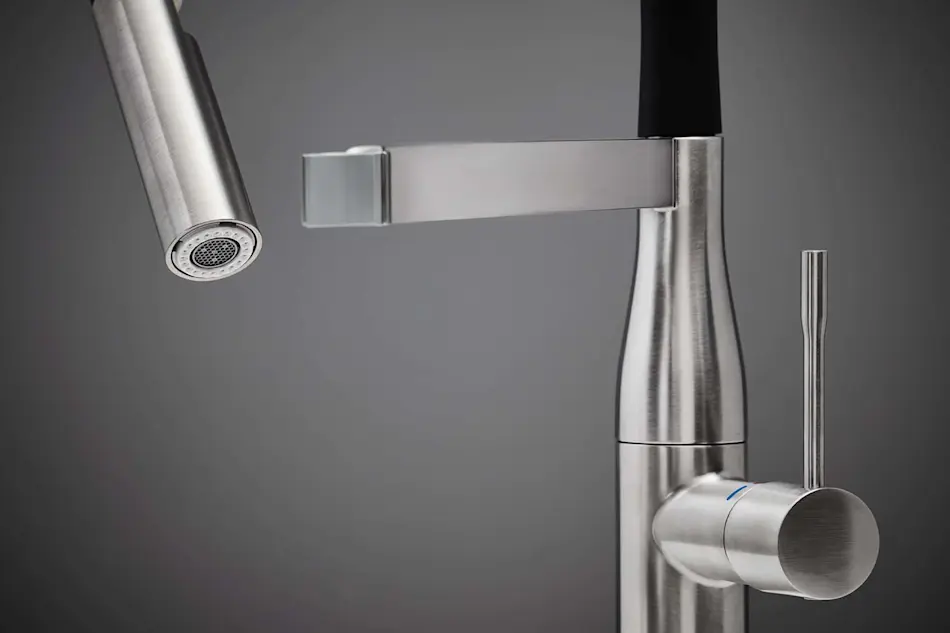Modern stainless steel kitchen faucet with pull-down sprayer and cylindrical handle against gray background.