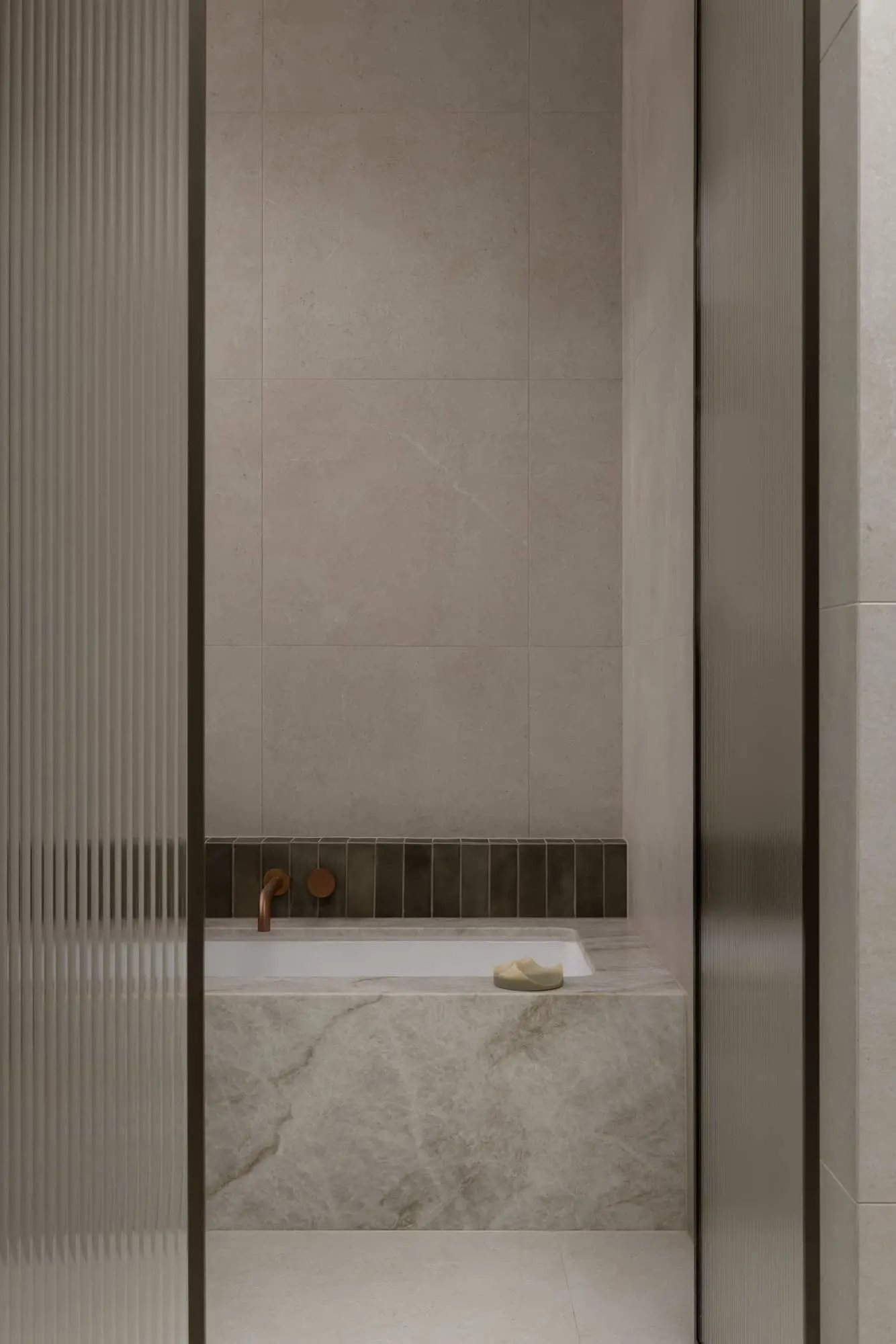 Modern bathroom with marble bathtub, copper fixtures, and beige stone tile walls viewed through textured glass door.