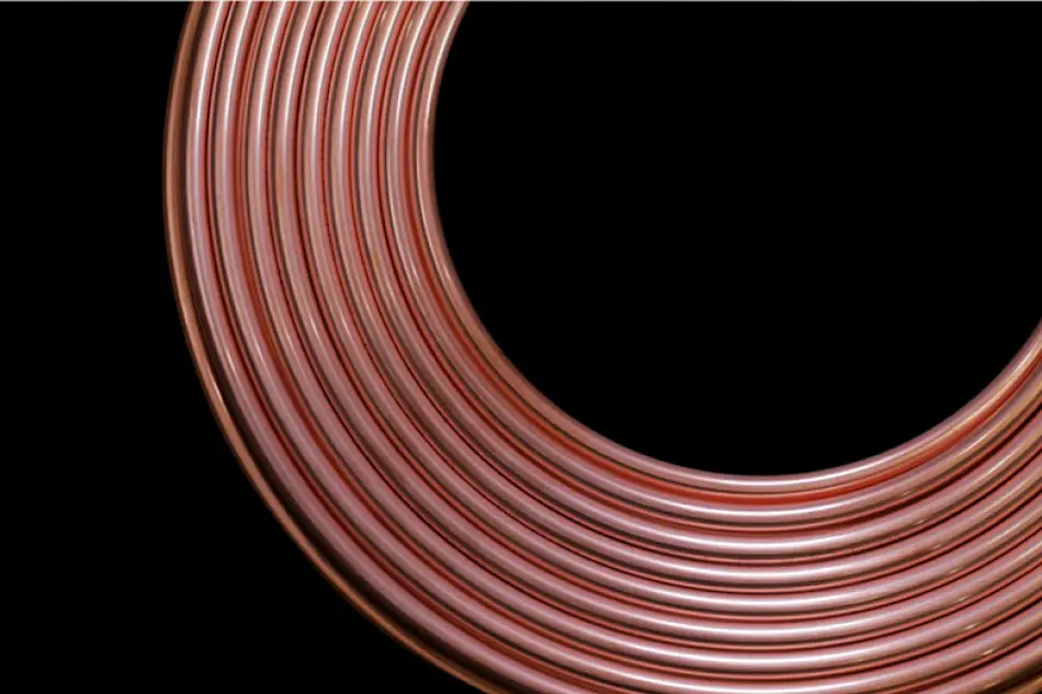 Coiled copper tubing or pipe forming a curved shape against a black background, showing shiny metallic surface.
