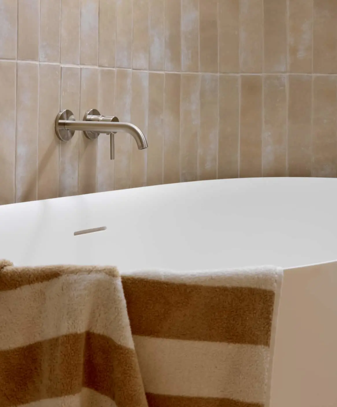 Modern bathroom with white soaking tub and wall-mounted faucet.