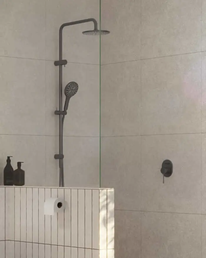 Modern bathroom shower with matte black rainfall showerhead and handheld sprayer against light gray tiled walls.