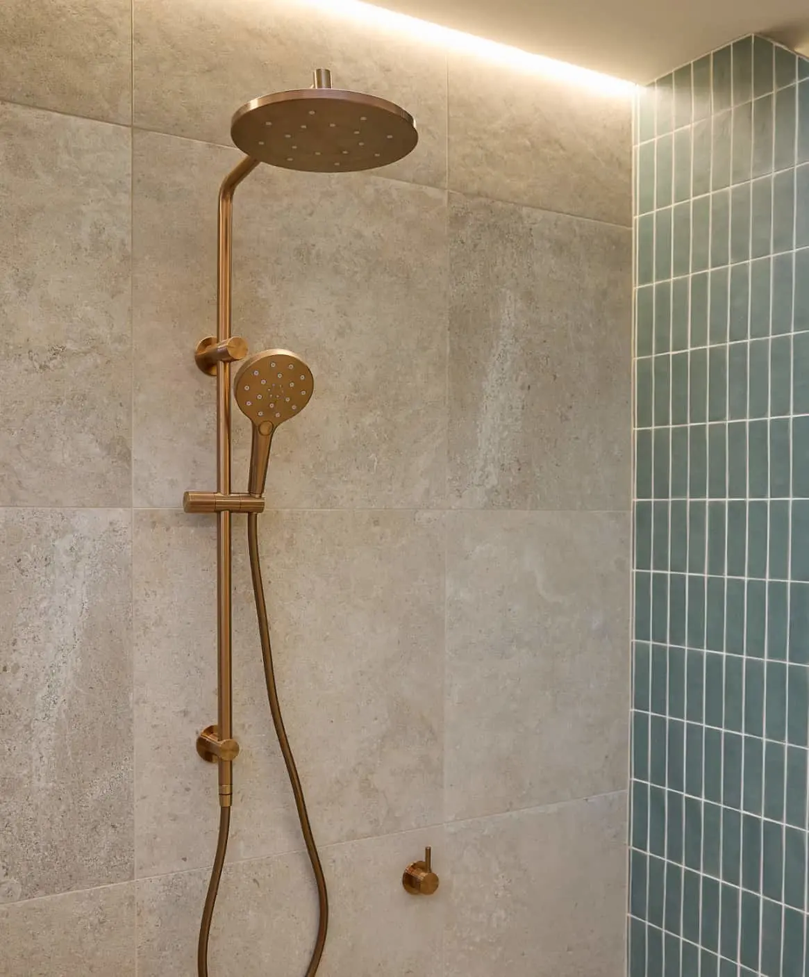Modern bathroom with bronze shower fixtures, teal vertical tiles, and wooden vanity with concrete basin.