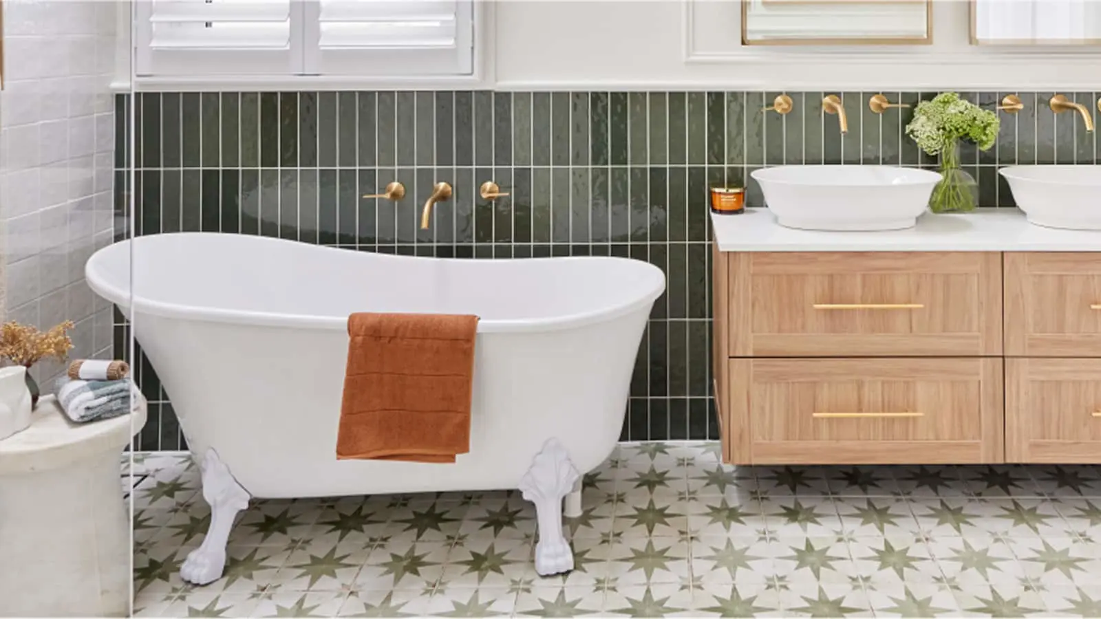 Modern bathroom with white clawfoot tub, green tile backsplash, wooden vanity, and star-patterned floor tiles.