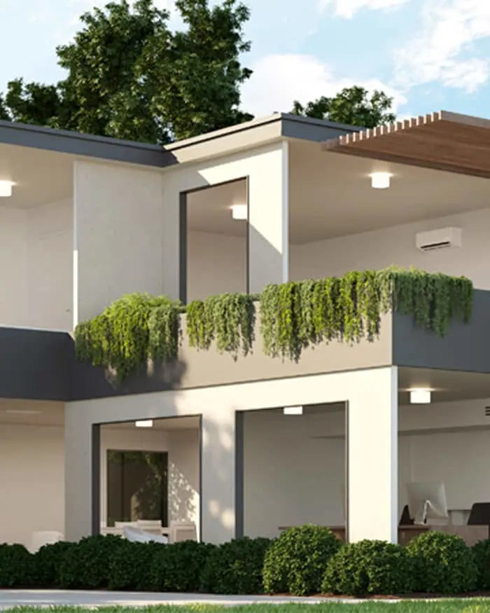 Modern two-story white house with balcony featuring hanging plants, large windows, and shrubs in front under blue sky.