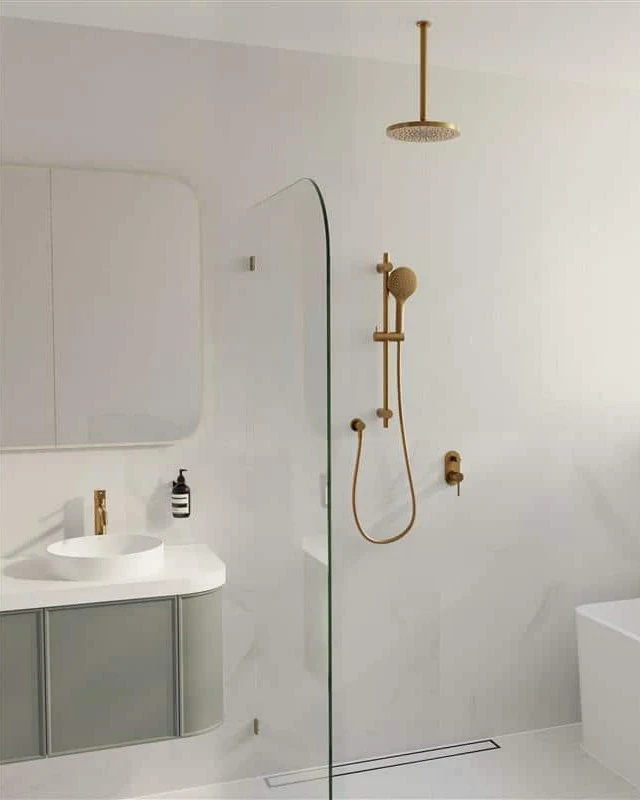 Modern white bathroom with glass shower partition, gold fixtures, ceiling-mounted showerhead, sink vanity, and bathtub.