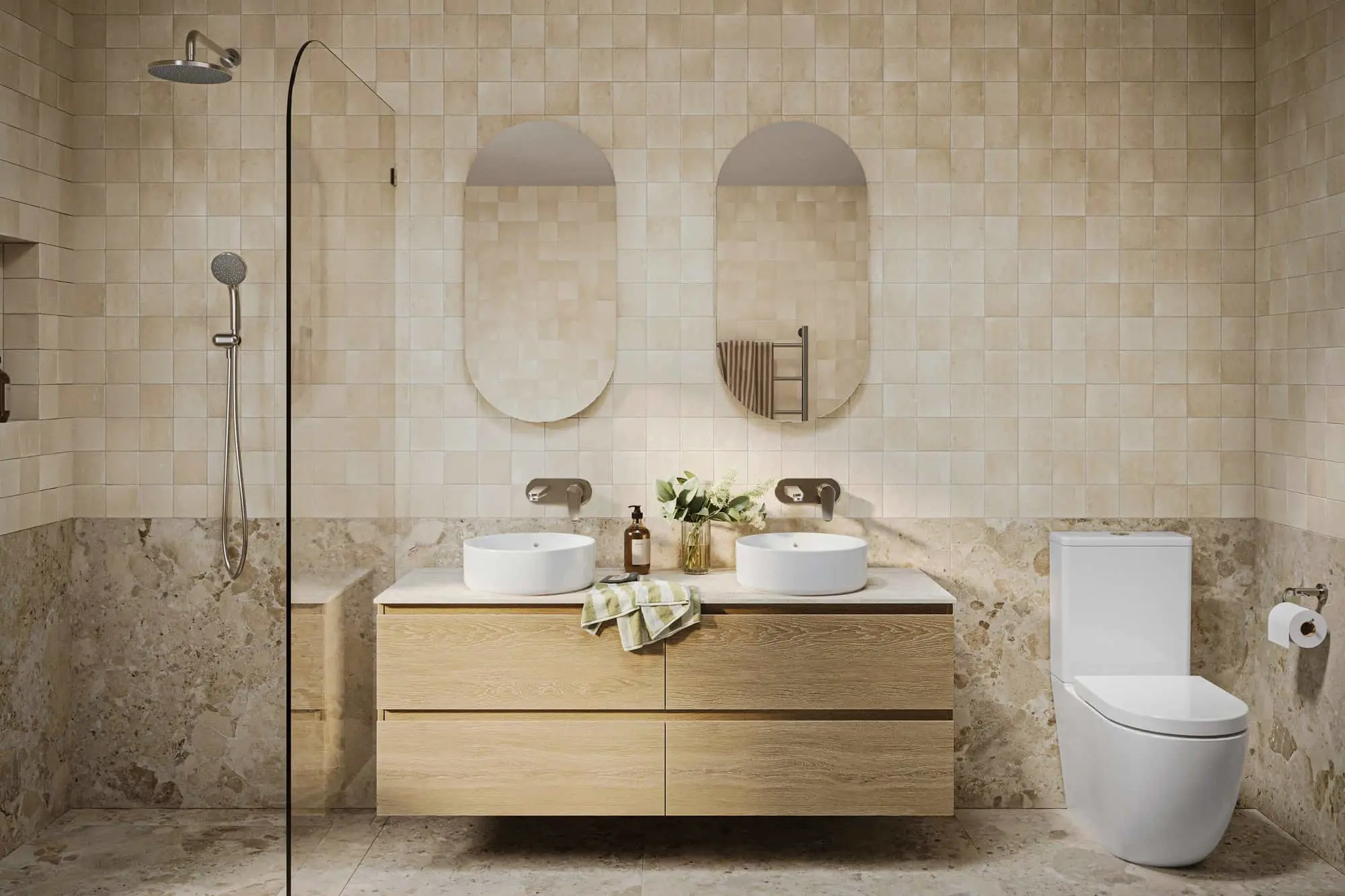 Modern bathroom with beige tile walls, double vanity with oval mirrors, glass shower, and white toilet.