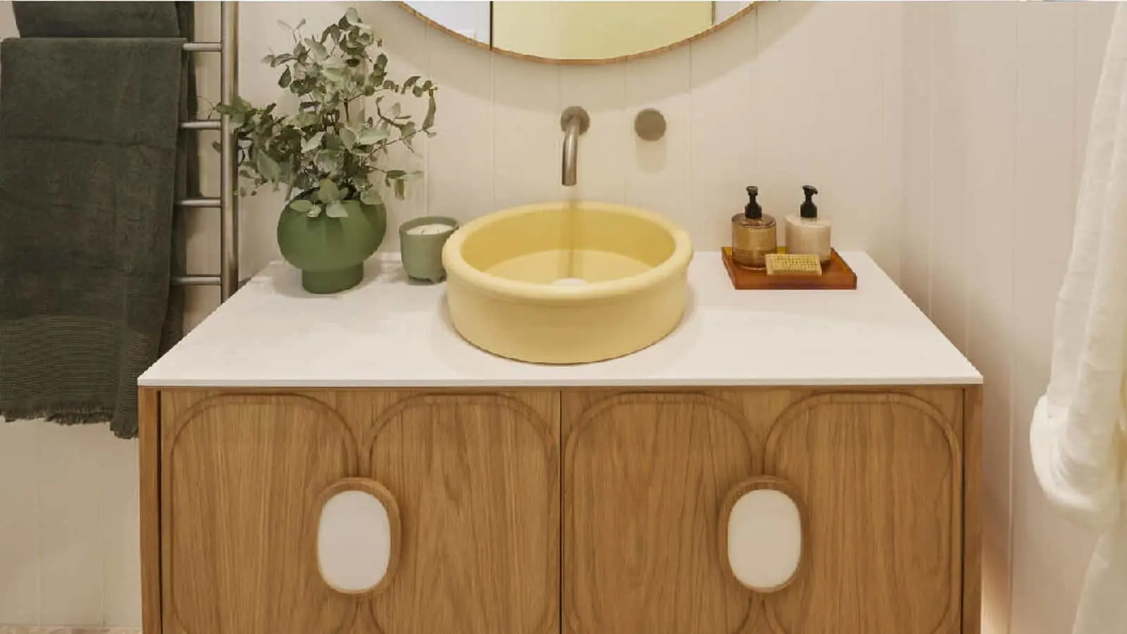 Modern bathroom vanity with yellow circular sink, wooden cabinet, green plant, and toiletry tray on white countertop.