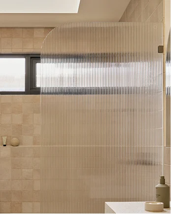 Modern bathroom with textured glass shower partition and beige tiled walls