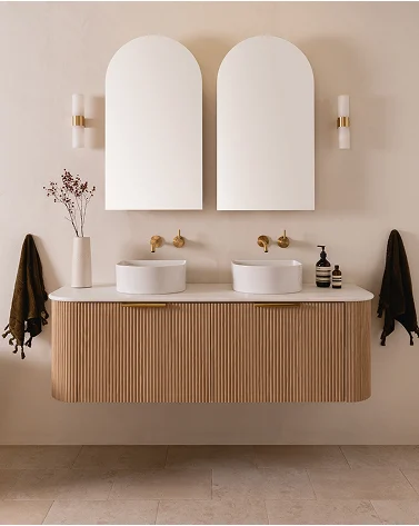 Modern bathroom with twin arched mirrors, wooden vanity with vessel sinks, brass fixtures, and minimalist decor.