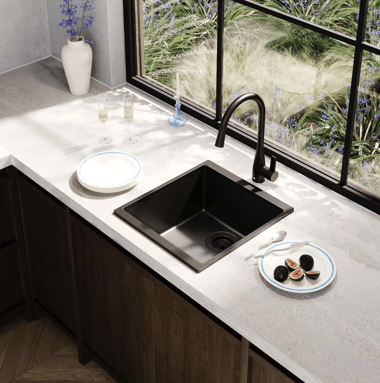 Modern kitchen with black sink, white countertop, sliced figs on plate, and large window overlooking ornamental grasses.