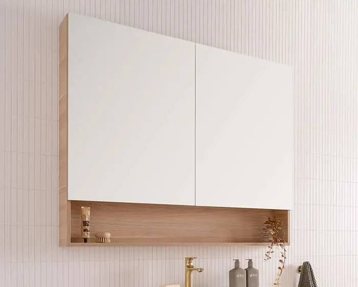 White bathroom cabinet with wooden shelf niche mounted on textured white wall, featuring minimal decor items.