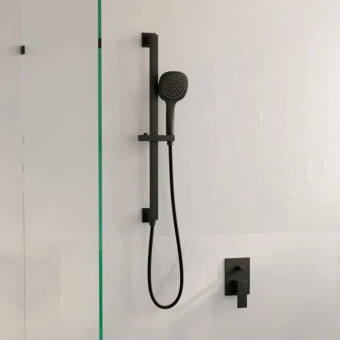 Modern black handheld shower head with adjustable rail mounted on white tiled bathroom wall next to glass panel.