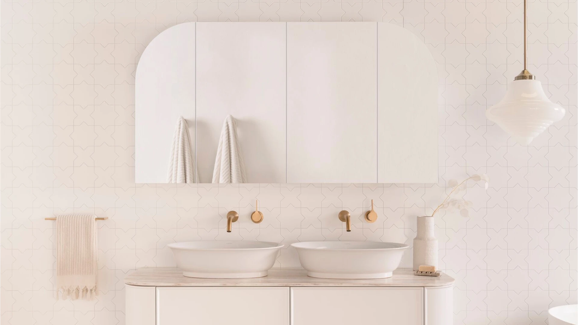 Modern white bathroom with dual vessel sinks, brass fixtures, and a large mirror cabinet against patterned wall tile.