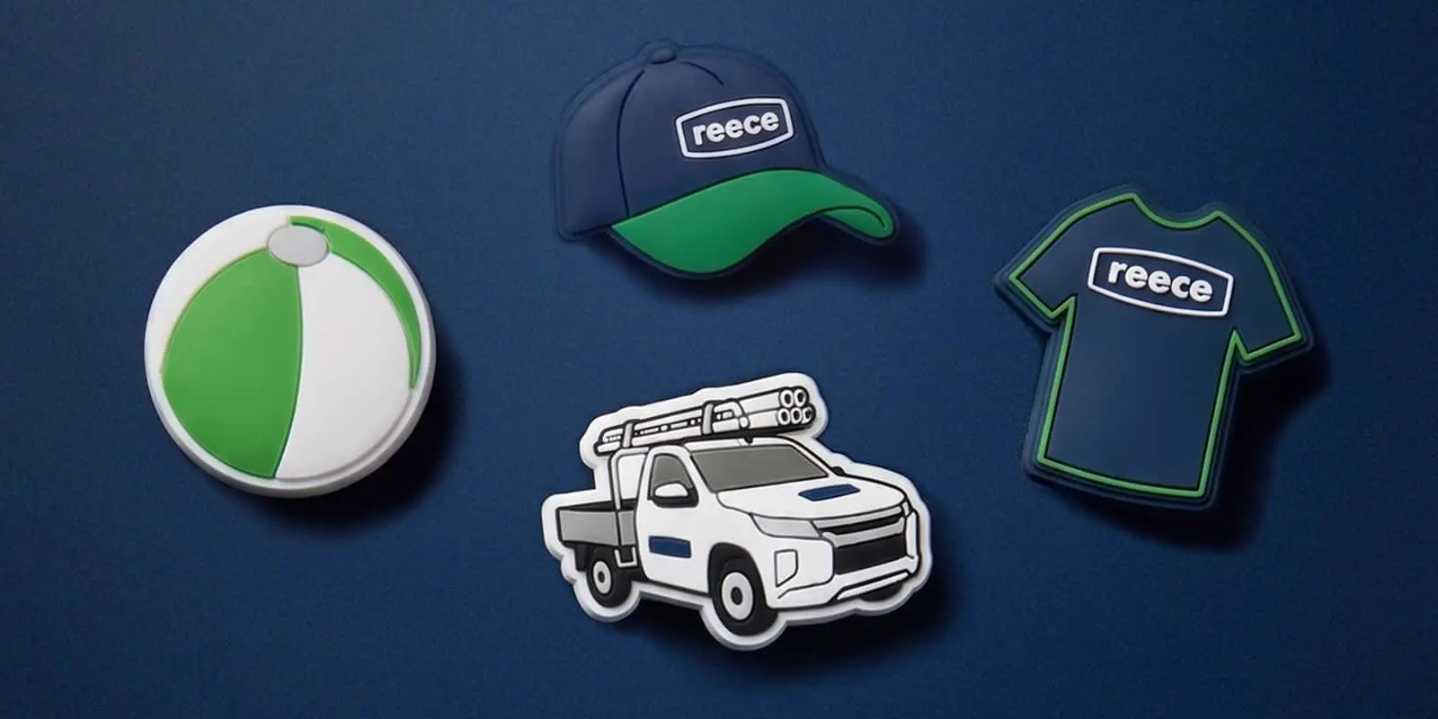 Four rubber Croc charms on a navy background: a green and white ball, a Reece cap, a ute, and a Reece t-shirt.